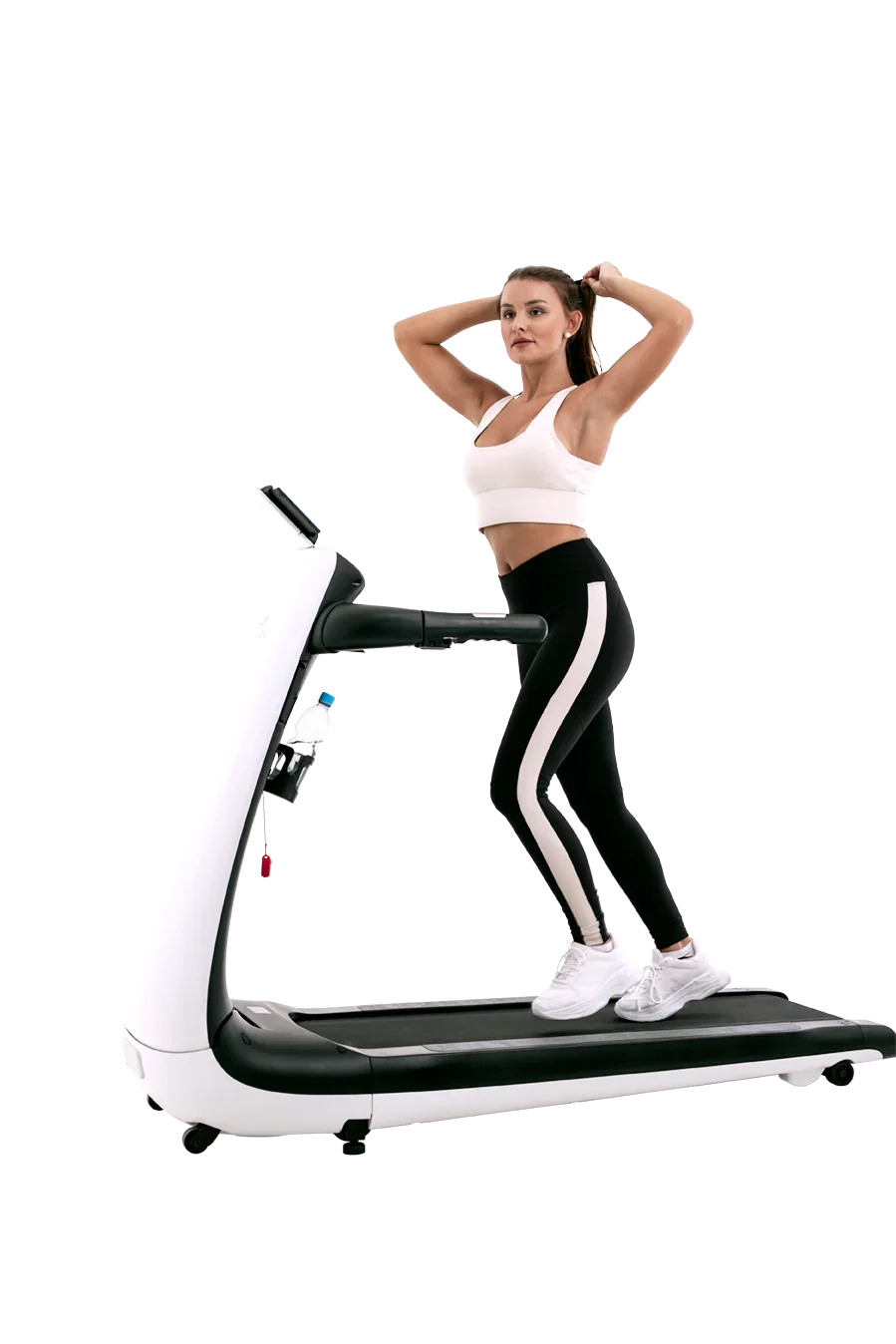 Woman in activewear standing on modern treadmill, tying hair, fitness equipment indoors